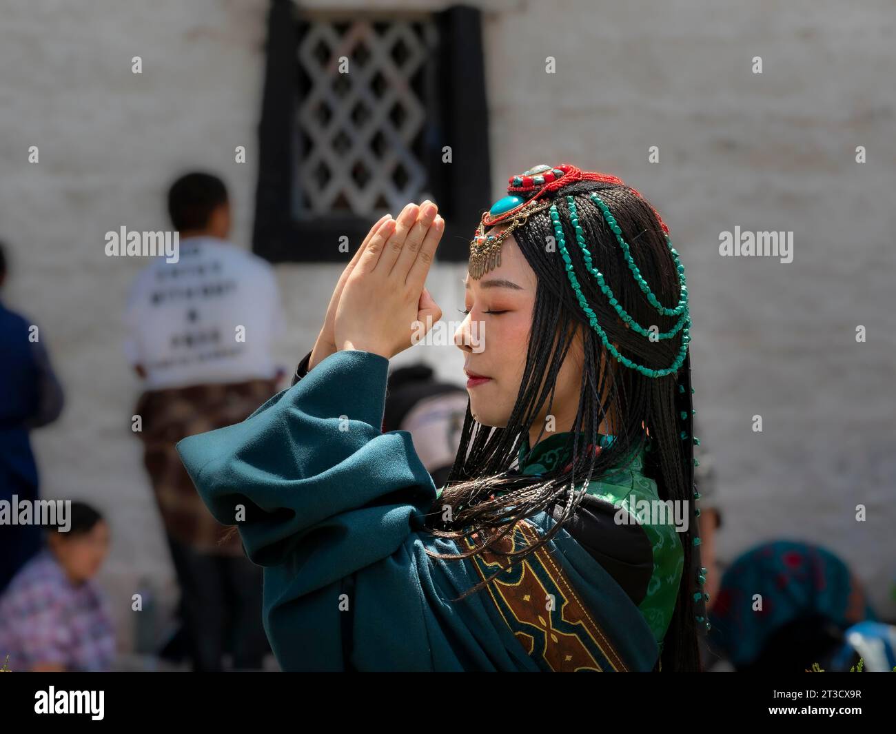 Tibetan young woman with festival clothes, hair ornaments and necklaces, praying hands, Lhasa, Tibet, China Stock Photo