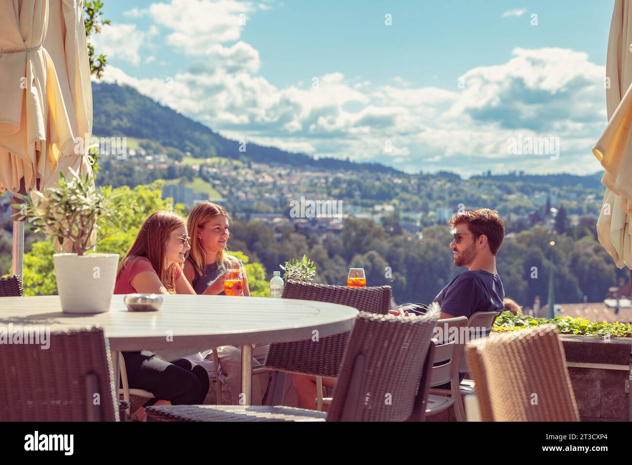 Bern, Switzerland–Aug 2,2023: 3 young people tourists enjoying under sunshine at an outdoor restaurant, vacation Stock Photo