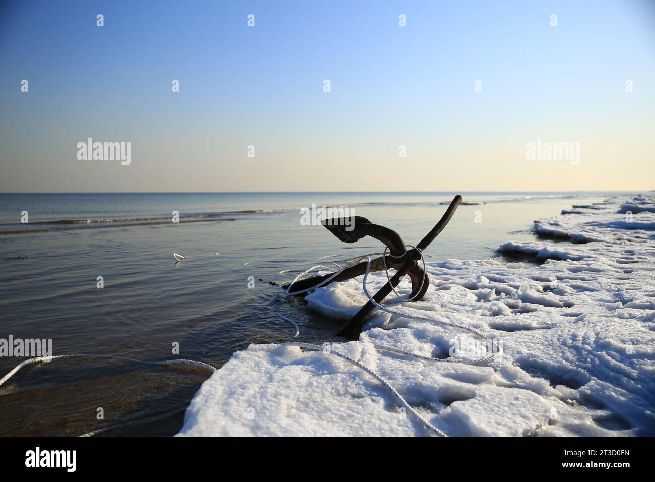 A close-up anchor at the icy ocean seashore Stock Photo