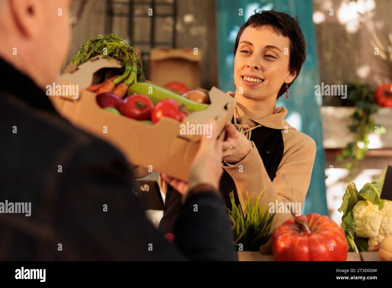 Young pleasant woman giving box full of fresh organic fruits and ...
