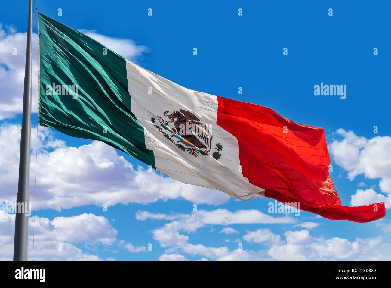 Flag of Mexico on a pole with a background of blue cloudy sky Stock Photo