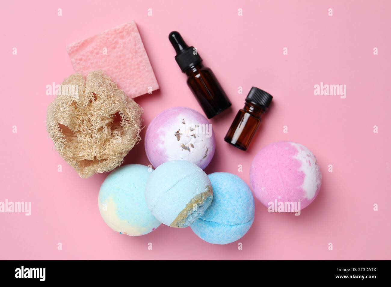 Bath bombs, loofah sponge, soap bar and bottles on pink background