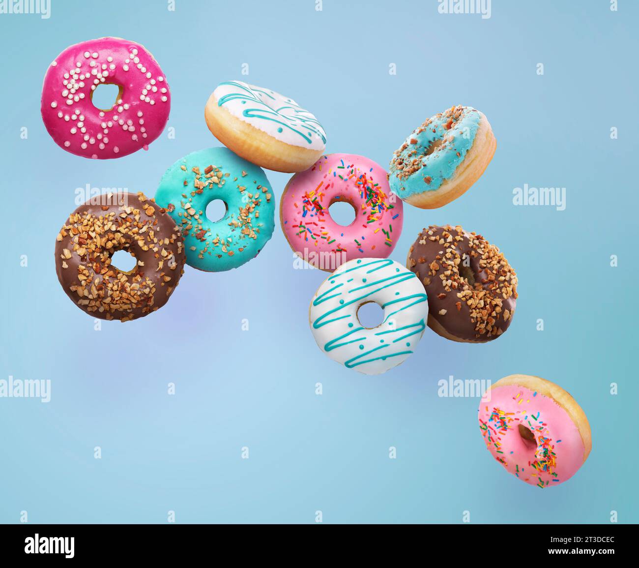 Different tasty donuts falling on light blue background Stock Photo