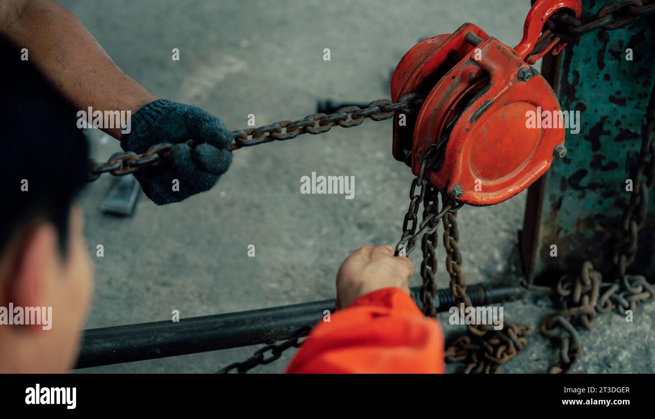 Mechanic testing strength and reliability of chain hoist for car towing