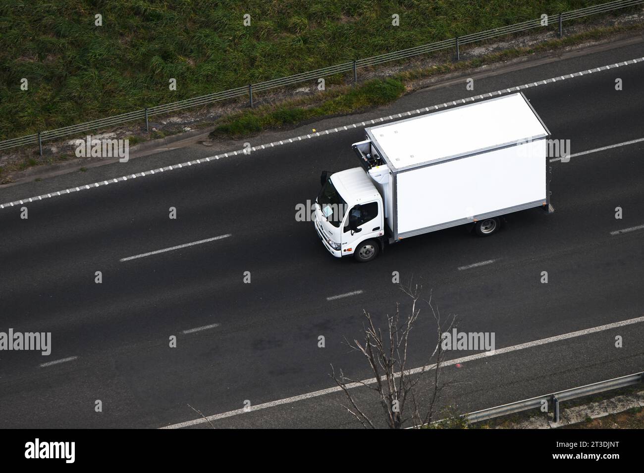 Aerial view of a white cold storage delivery truck on a highway, showcasing transportation and distribution. Stock Photo