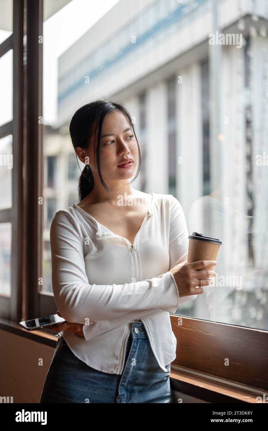 A portrait of a beautiful and thoughtful Asian woman stands by the ...