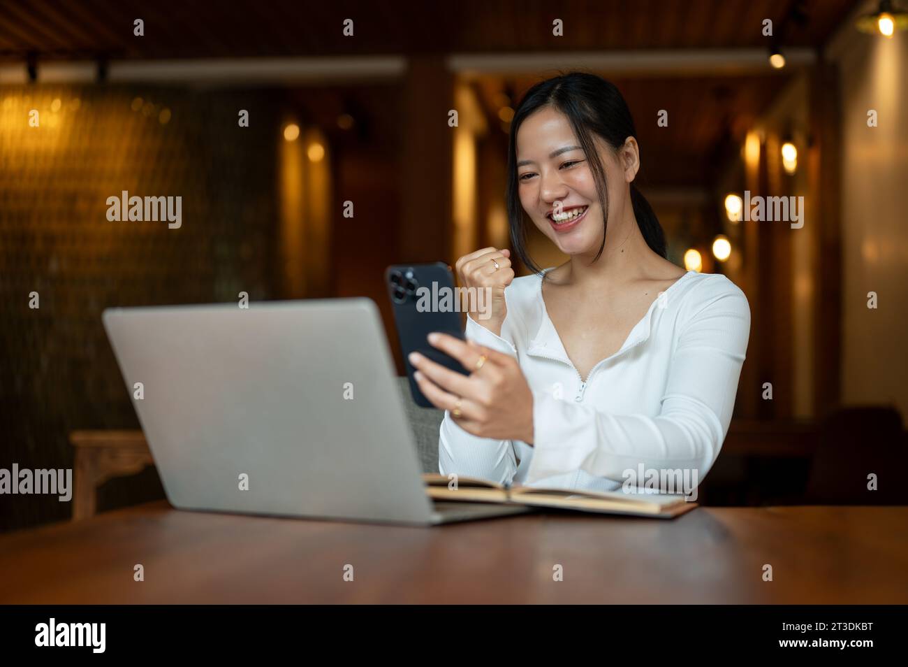 A cheerful and beautiful Asian woman is looking at her smartphone ...