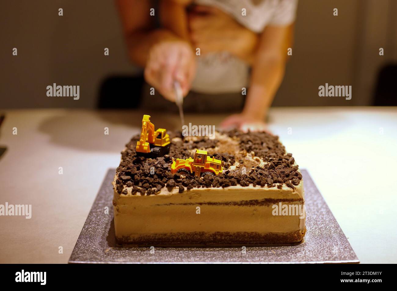 Midsection of mother and son cutting birthday cake Stock Photo