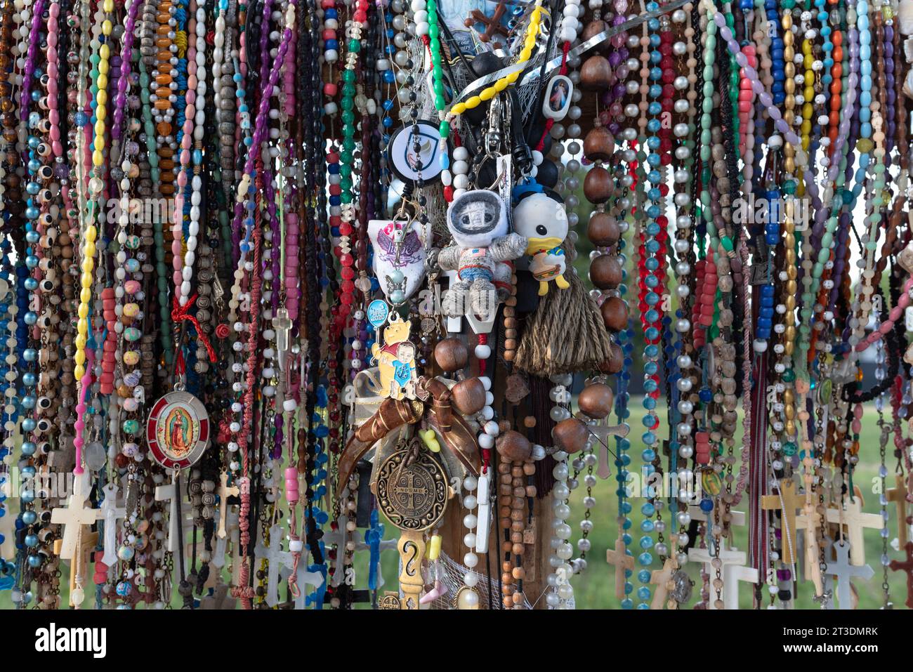 Closeup of rosaries, momentos and medallions hanging from a cross, honoring victims of the 2022 school shooting at Robb Elementary, Uvalde, Texas. Stock Photo