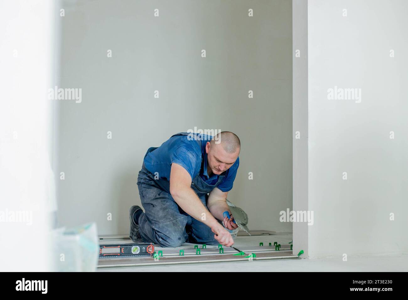 A male construction worker installs a large ceramic tile. Stock Photo