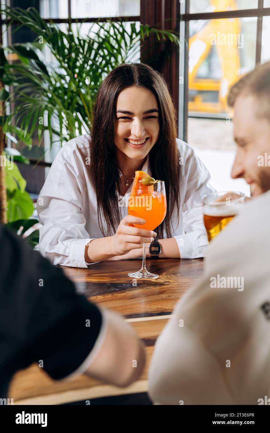 Smiling woman enjoying coctail in restaurant during rest with friends. Celebration and party concept Stock Photo
