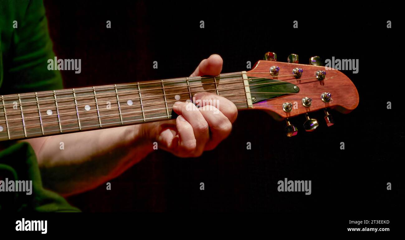 Image of fingers taking a chord on the fretboard of an acoustic guitar