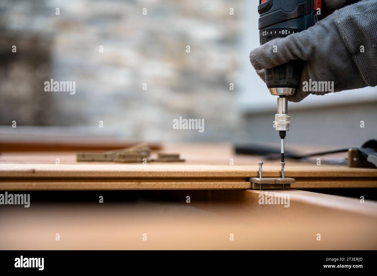 Closeup low angle view of an battery screwdriver fixating screws in plastic distance marker for wooden outside patio in a domestic rennovation concept Stock Photo