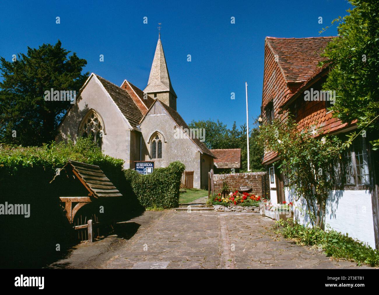 View W of Alfold Church, Surrey, England, UK, with Church Cottage to the R & the preserved C18th village stocks in a shelter to L of Rosemary Lane. Stock Photo