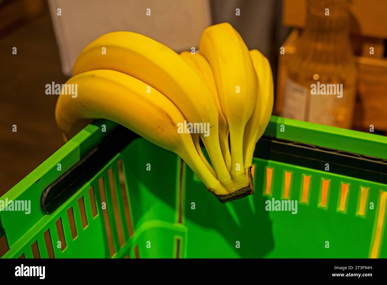 putting bananas in the green grocery basket in the supermarket Stock
