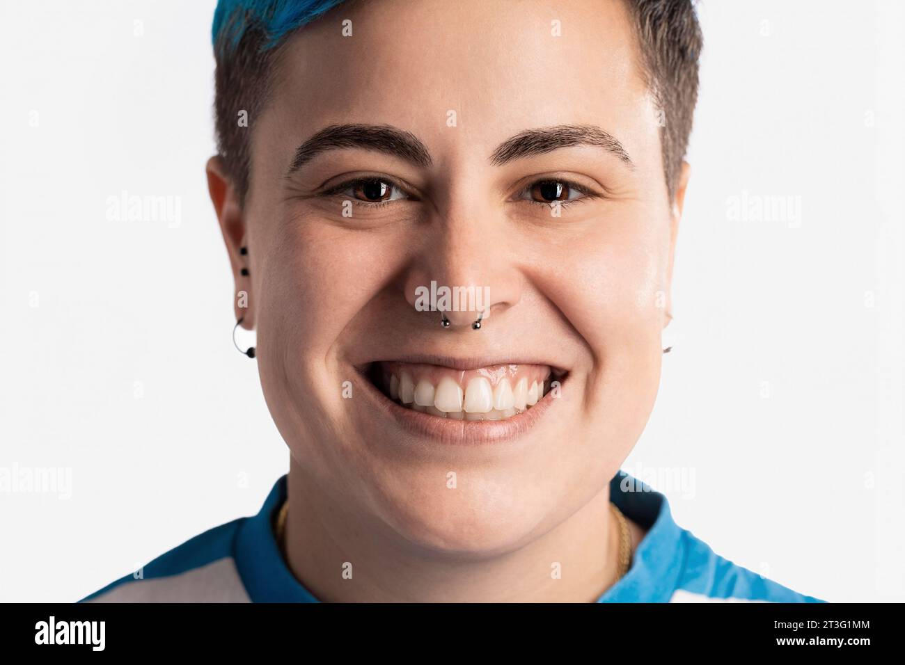 A captivating close-up of a genderfluid individual radiating joy. Their vibrant blue hair and contemporary piercings reflect their authentic expressio Stock Photo
