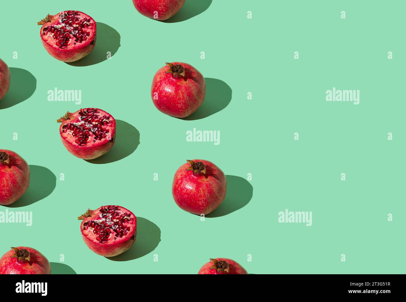 Trendy fruit pattern made of fresh red pomegranates on light pastel