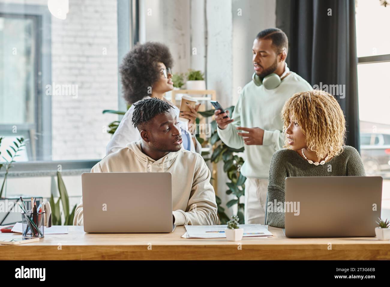 four african american friends in casual outfits discussing their project actively, working process Stock Photo