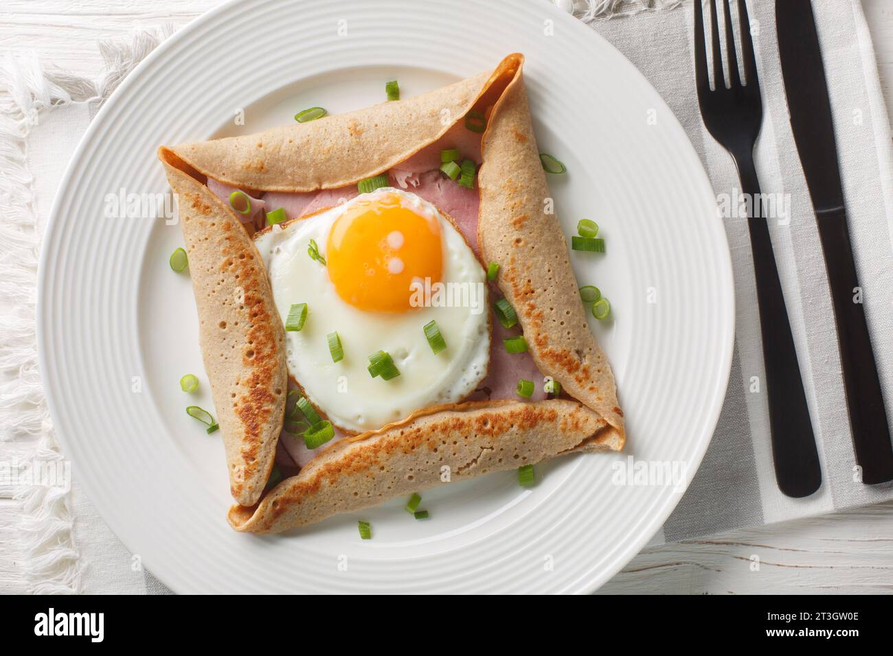 Breton crepe, Savory Buckwheat Galettes Bretonnes with fried egg, cheese, ham closeup on the plate on the table. Horizontal top view from above Stock Photo