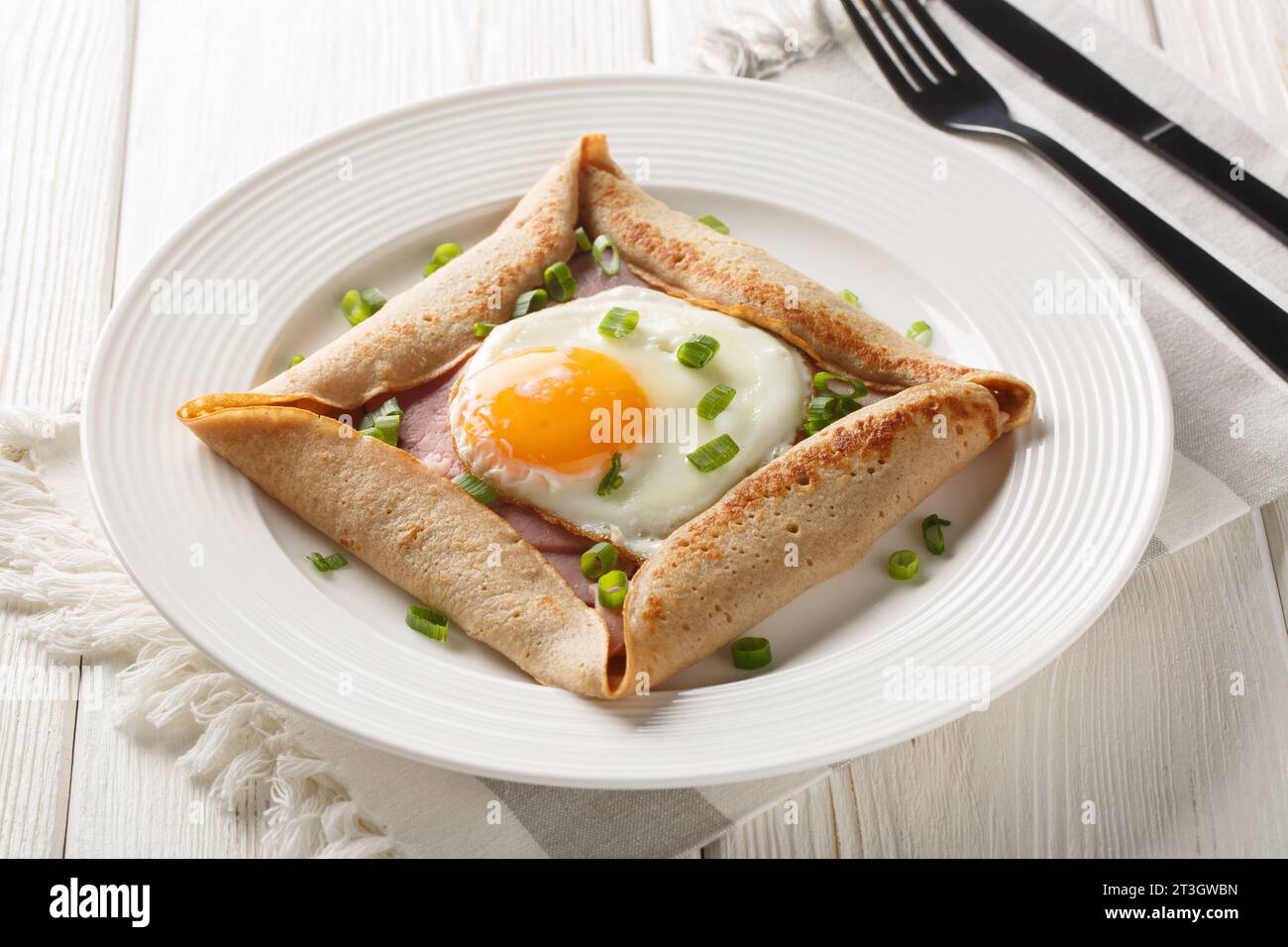 Breton crepe, Savory Buckwheat Galettes Bretonnes with fried egg, cheese, ham closeup on the plate on the table. Horizontal Stock Photo
