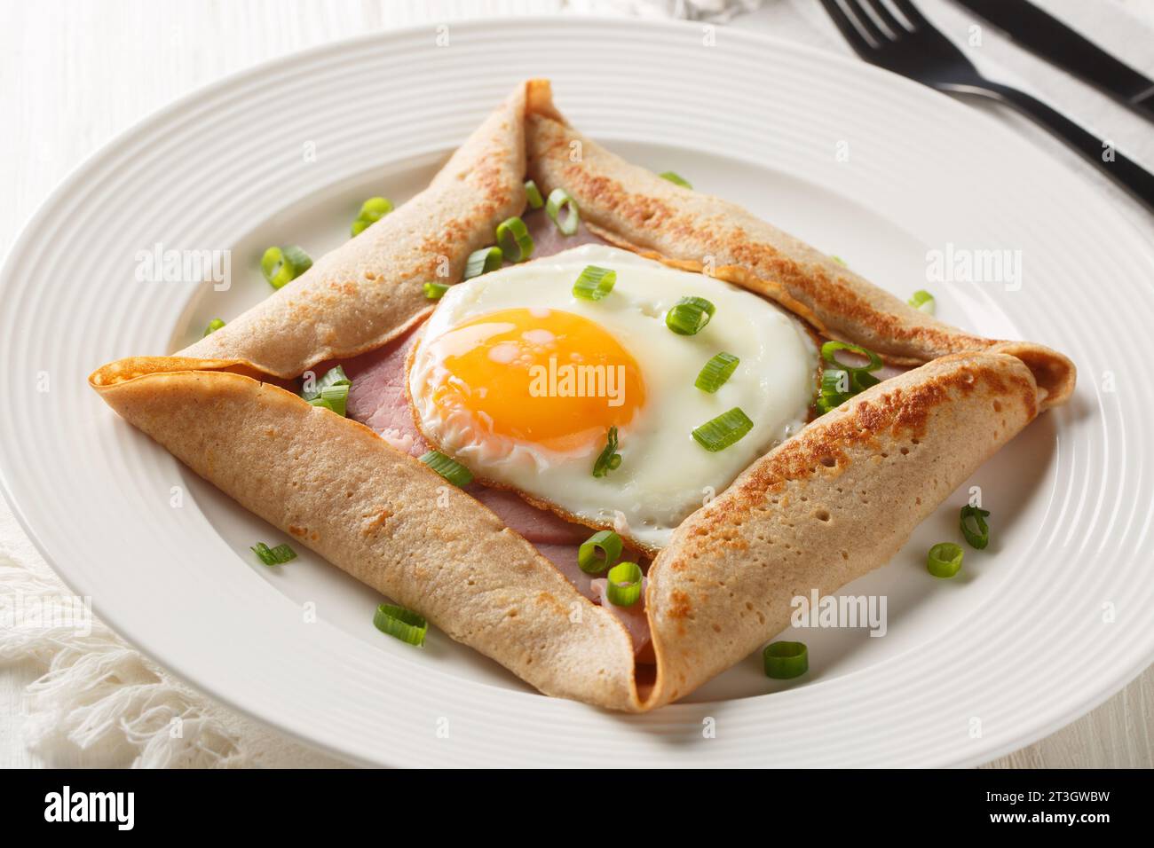 Galette complete Breton buckwheat pancake with egg cheese and ham closeup on the plate on the table. Horizontal Stock Photo