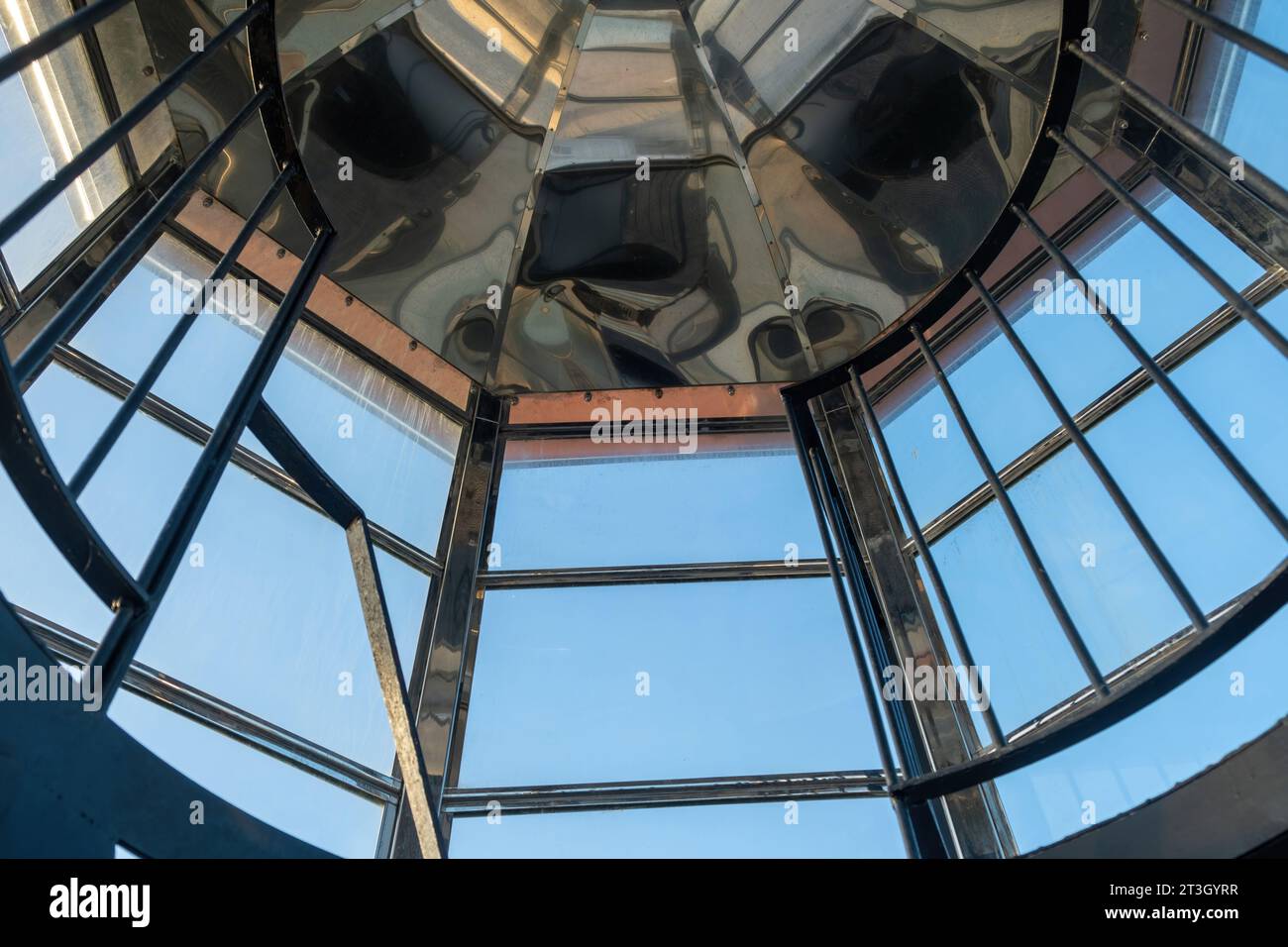 Interior top of Gavdos Lighthouse, Crete island Greece. Under view from ladder end of metal reflective frame construction and blue sky. Stock Photo