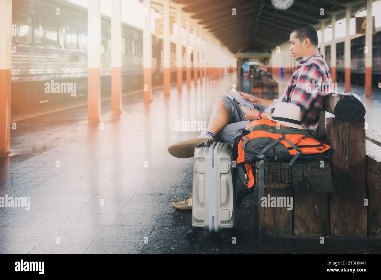 Traveler sitting and using map at train station. Stock Photo
