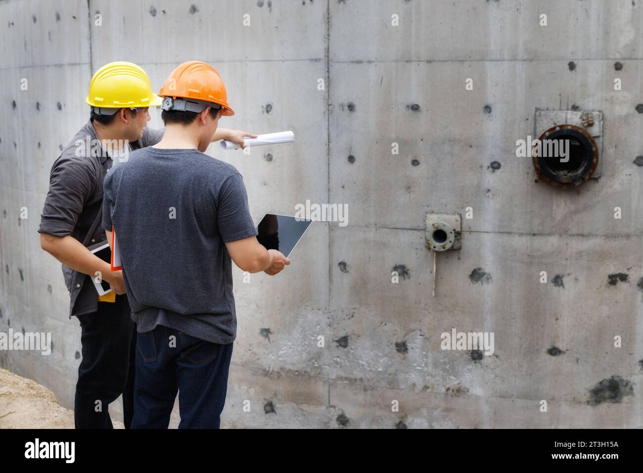 Team of construction workers discussing project details with blueprint in construction site. Stock Photo