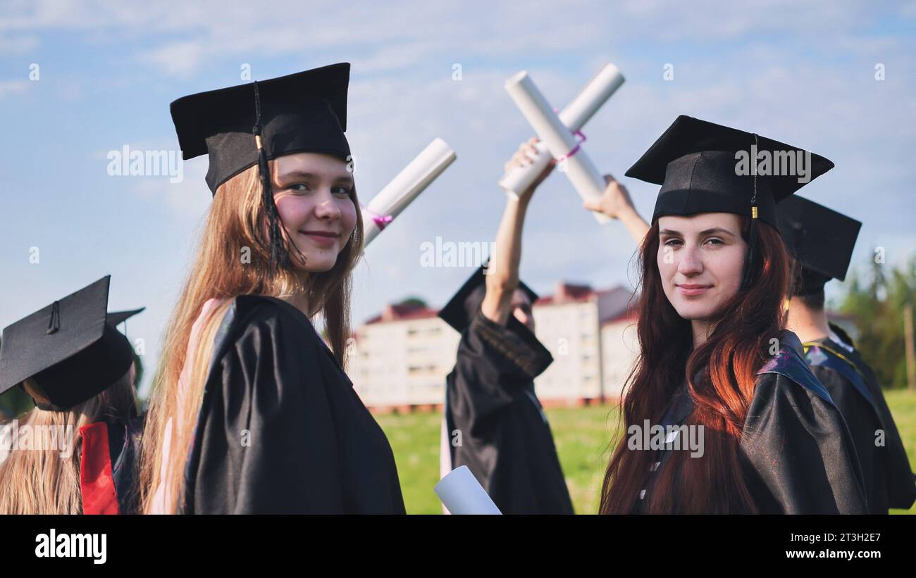 Portraits of graduating girls in black robes on the street. Stock Photo