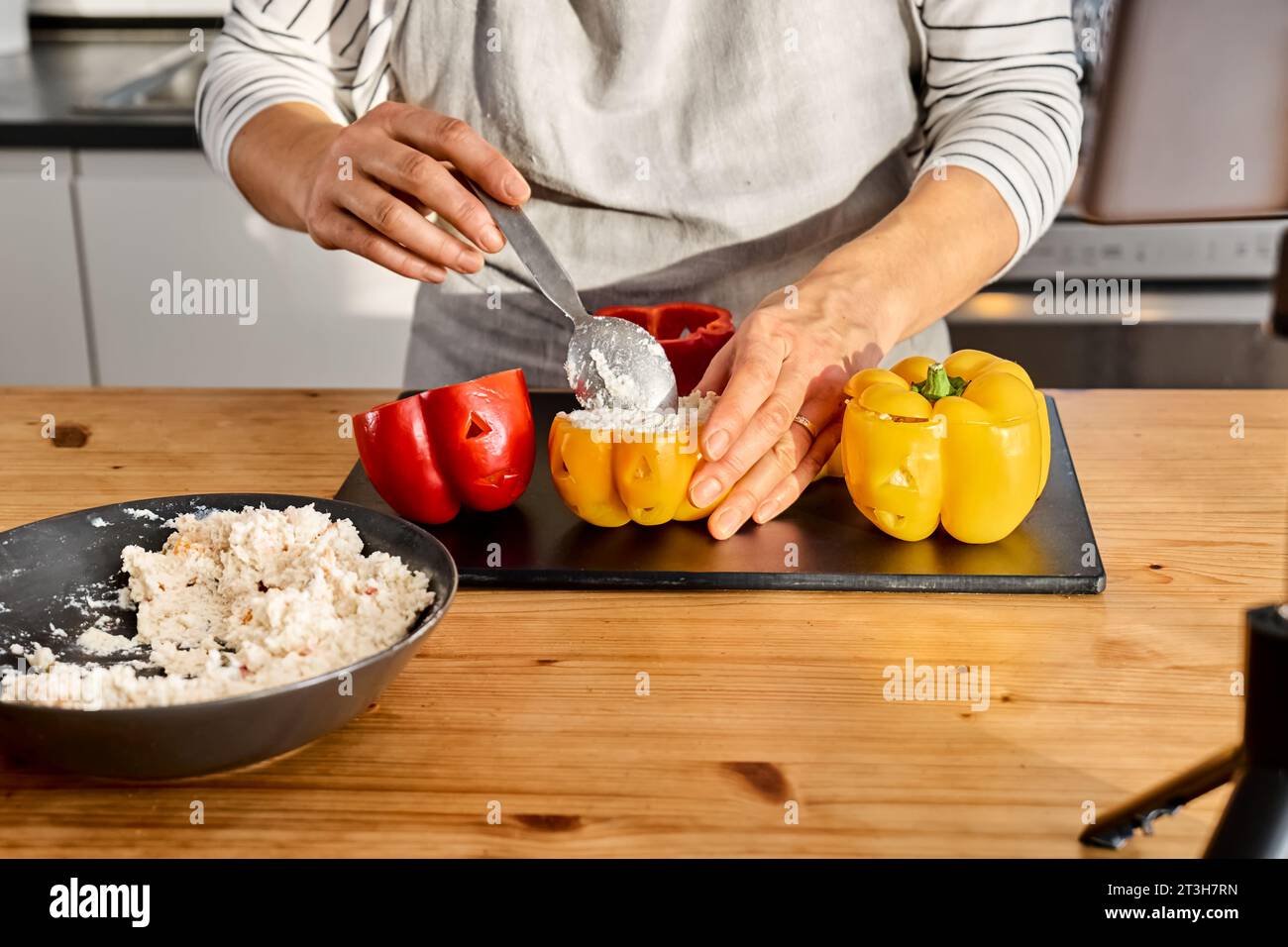 Woman food blogger preparing stuffed colorful bell peppers with ricotta cheese for Halloween party. Peppers carved like Jack-o-lantern scary face. Hal Stock Photo