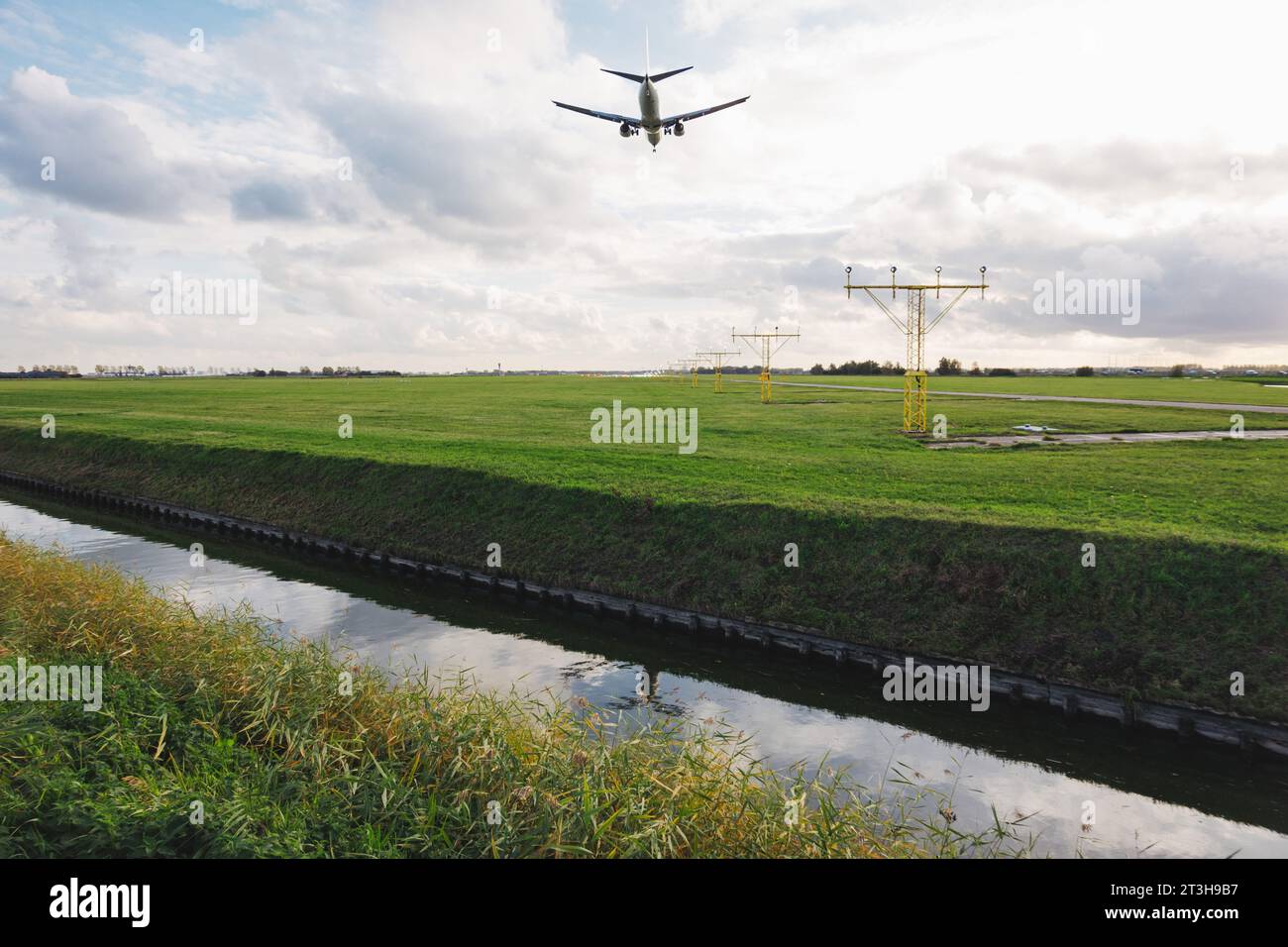 an Airbus A320 jet on approach to Amsterdam Schiphol airport's Polderbaan runway, which is separated from public areas by a canal Stock Photo