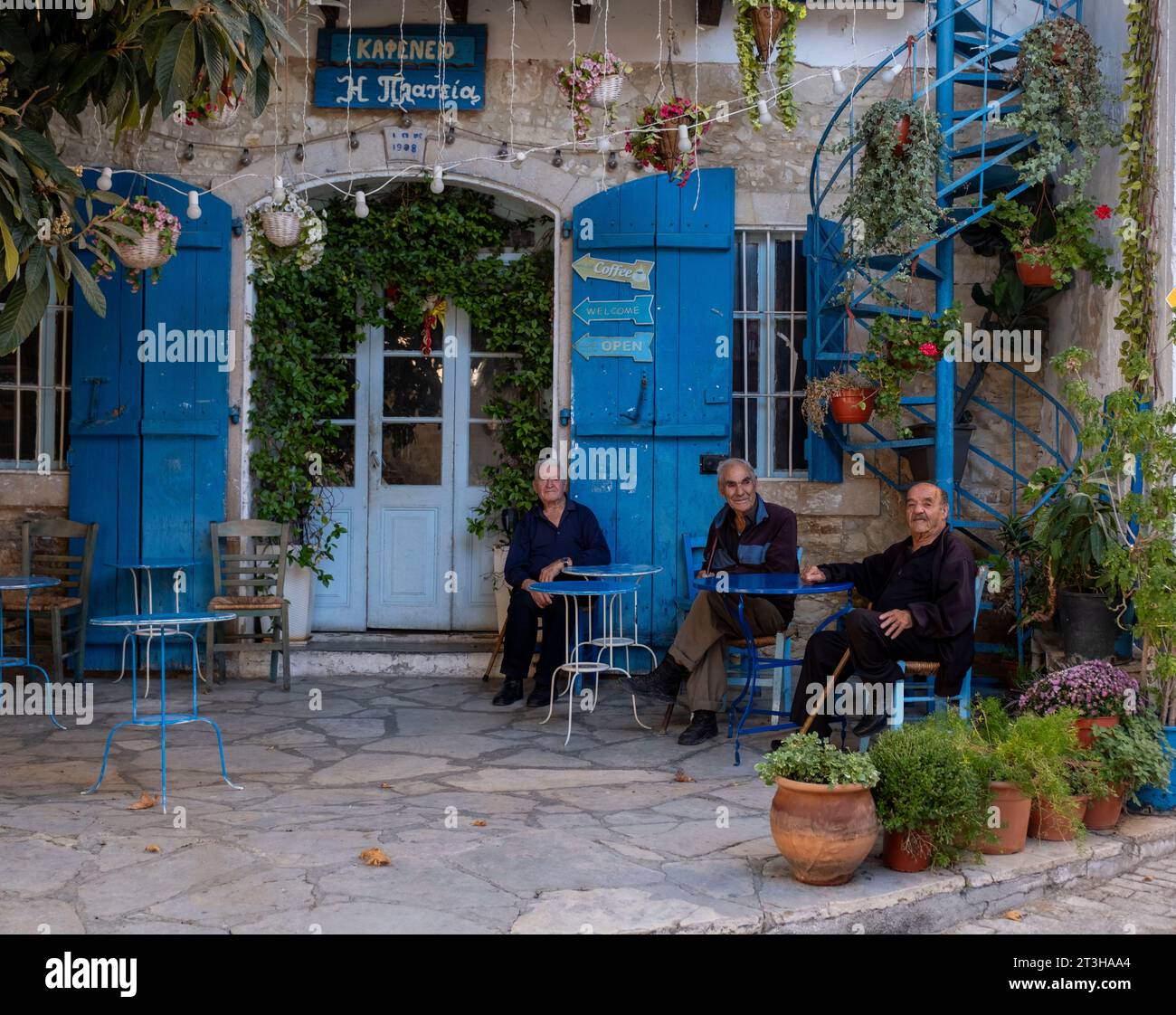 Senior men sit chatting outside the Historic Plateia (The Square) Coffee House in Vouni village, Limassol district, Cyprus. Stock Photo