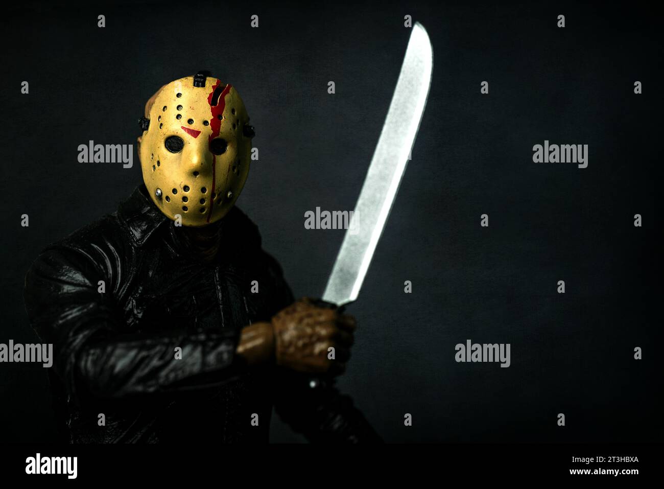 Close-up of figure of Jason Voorhees with machete main character of the film series Friday the 13th over grey background. Illustrative editorial Stock Photo