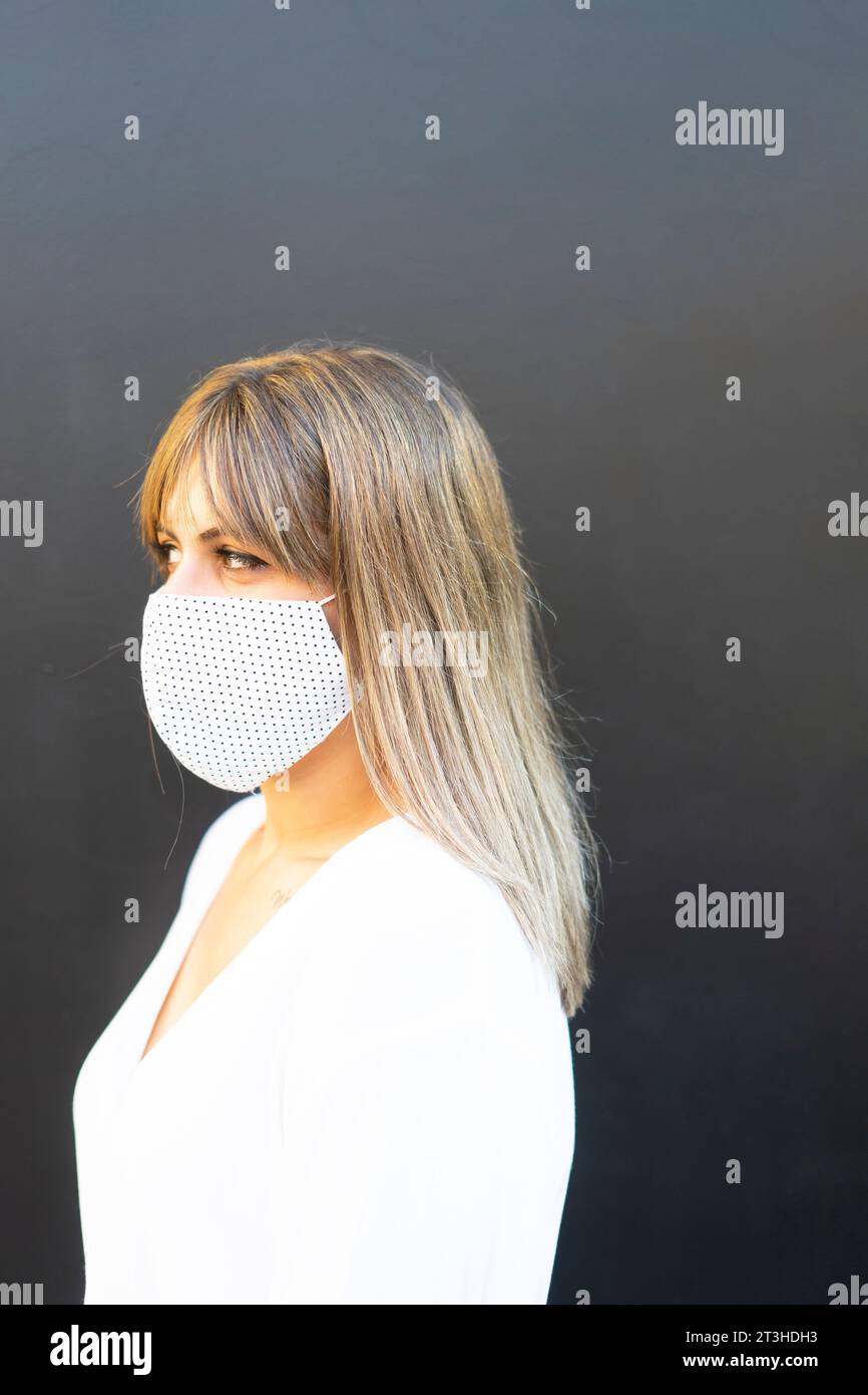 Front view portrait of serious woman with protective mask avoiding contagion looking at the side of the street Stock Photo