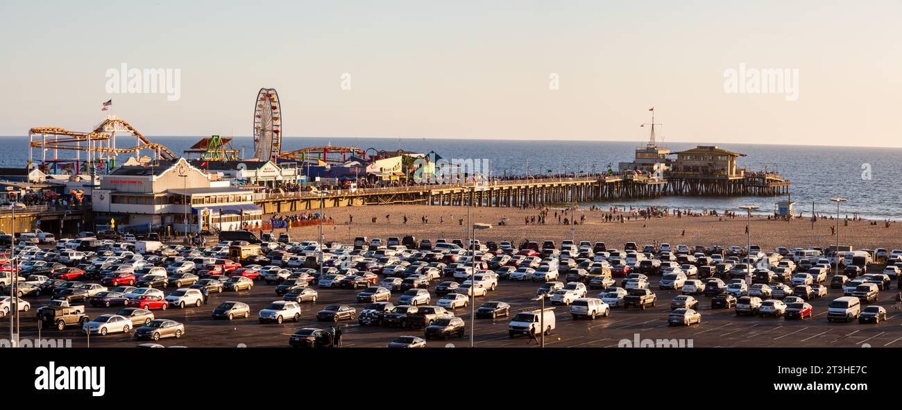 Panoramic view over Santa Monica Pier and Ocean Park amusements at late afternoon. Car parking lot in front Stock Photo