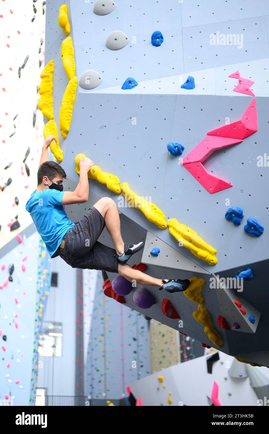 Man wearing a COVID19 pandemic mask climbs a bouldering wall in a