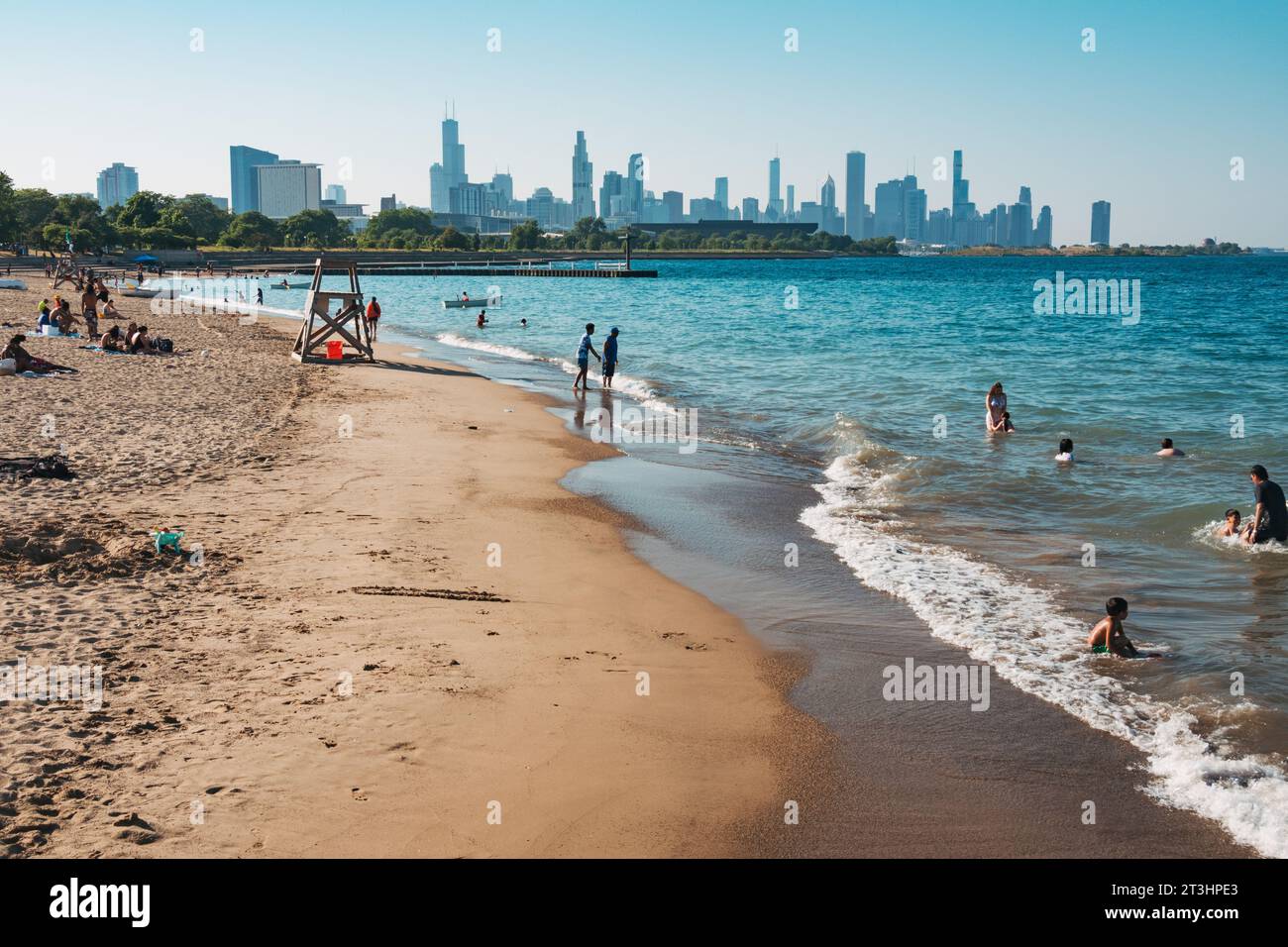 the Chicago skyline seen from 31st Street Beach. Beachgoers make the most of a warm summer day in Lake Michigan Stock Photo
