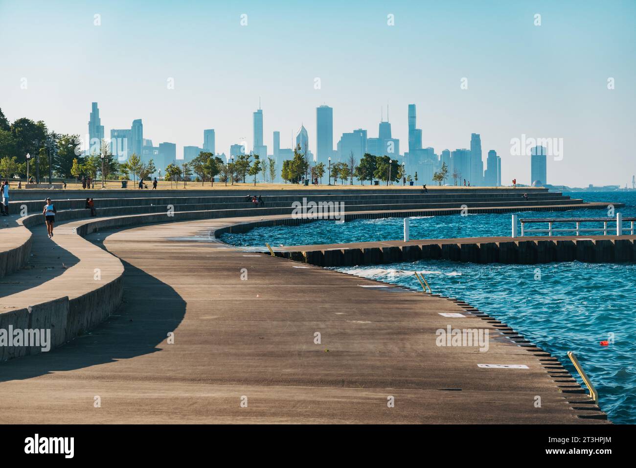 a grassy area with a walking path lined by trees at Burnham Park on the Lakefront Trail in Chicago, United States Stock Photo