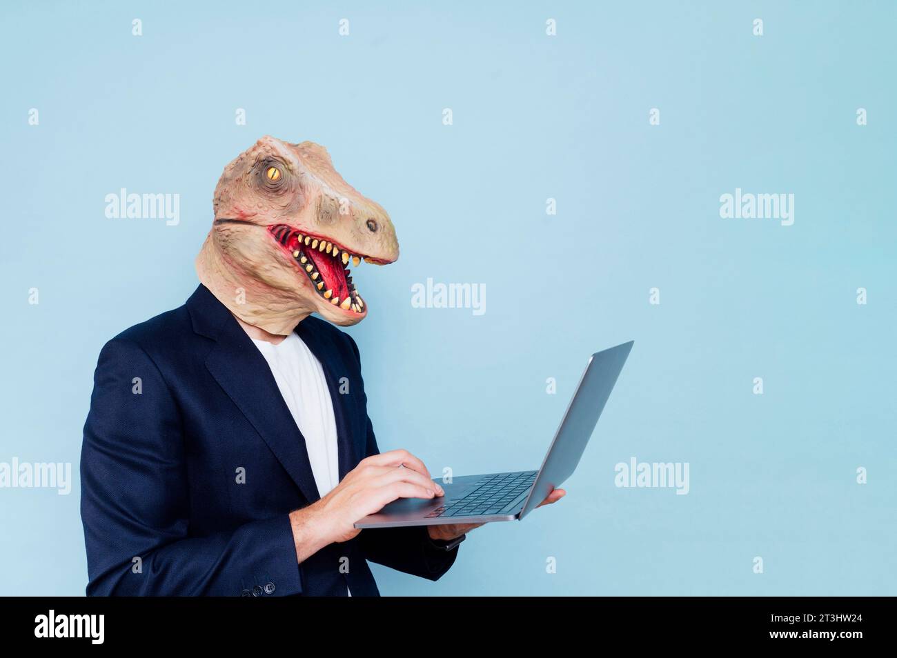 man in dinosaur mask using laptop Stock Photo