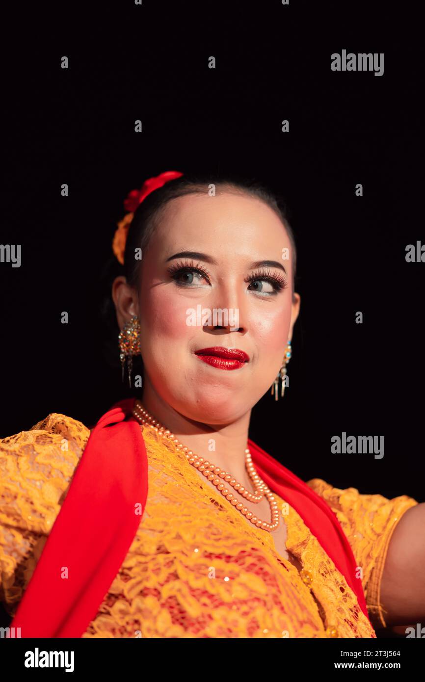 Indonesian woman in makeup with red lips wearing a golden necklace and golden earrings before dancing on the stage Stock Photo