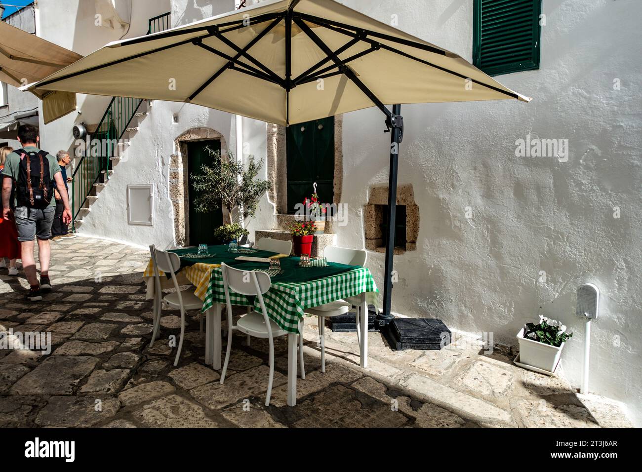 An empty restaurant table covered in green gingham,  ready for customers in Ostuni, Italy. Stock Photo