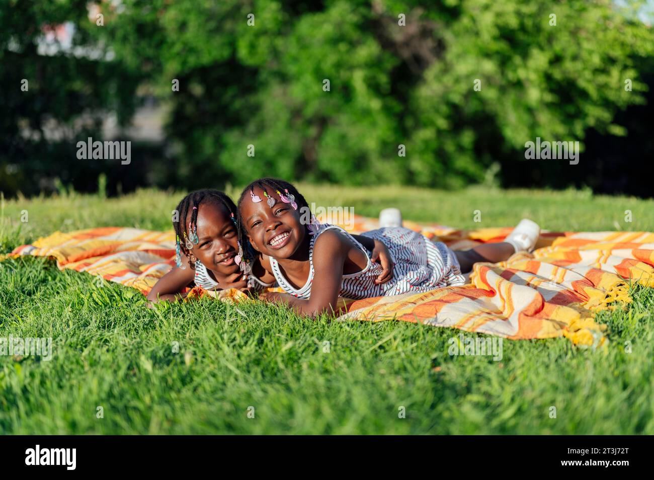 African American girls lying down looking at camera in park Stock Photo