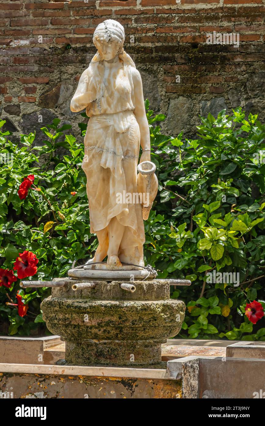 Guatemala, La Antigua - July 20, 2023: Museum Casa Santa Domingo. Closeup water fetching woman marble statue standing on dry fountain, backed by green Stock Photo