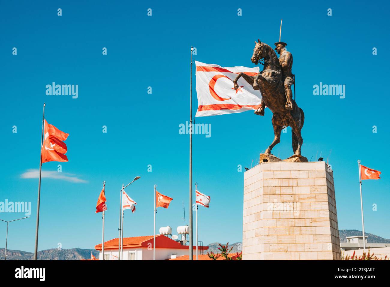 the Türkiye and Northern Cyprus flags fly next to a statue of Atatürk on horseback at a traffic roundabout in North Nicosia Stock Photo