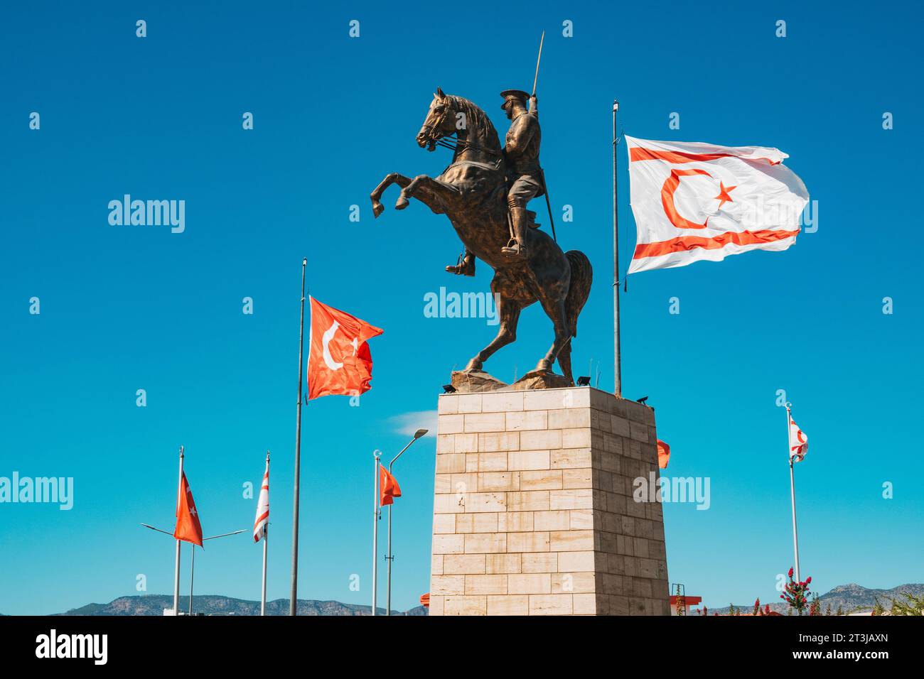 the Türkiye and Northern Cyprus flags fly next to a statue of Atatürk on horseback at a traffic roundabout in North Nicosia Stock Photo