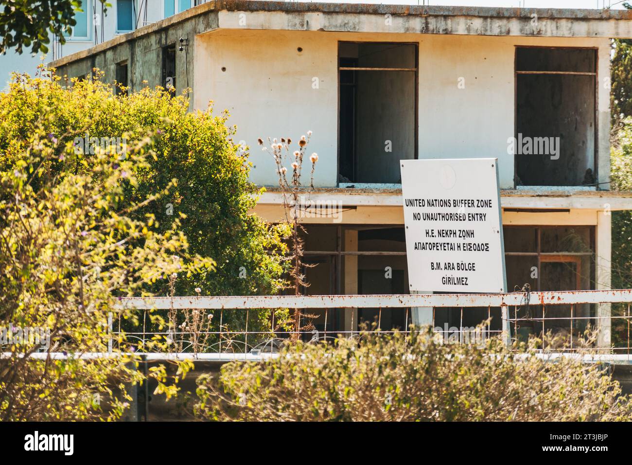 a sign reads 'United Nations Buffer Zone, No Unauthorised Entry' in front of an abandoned building at a border crossing on the island of Cyprus Stock Photo