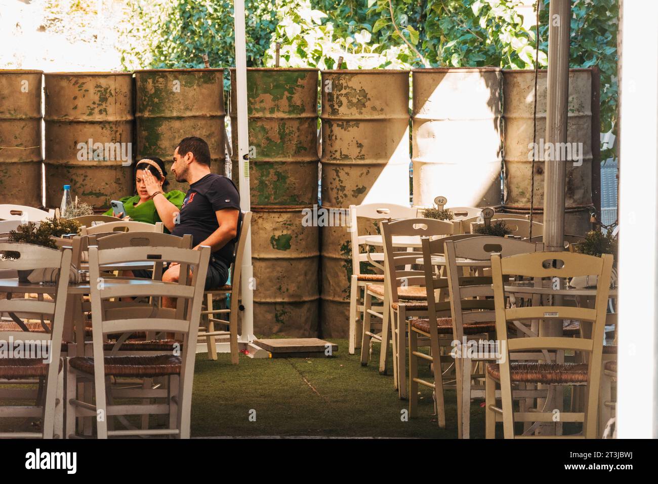 a couple dine at a restaurant right in front of cement-filled metal drums that mark the UN Buffer Zone border in southern Nicosia, Cyprus Stock Photo