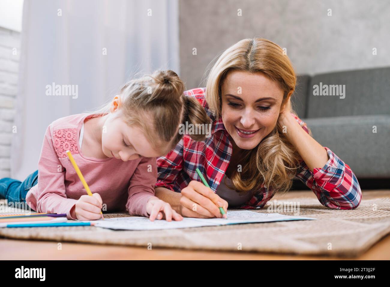 Beautiful mother daughter drawing together book home Stock Photo