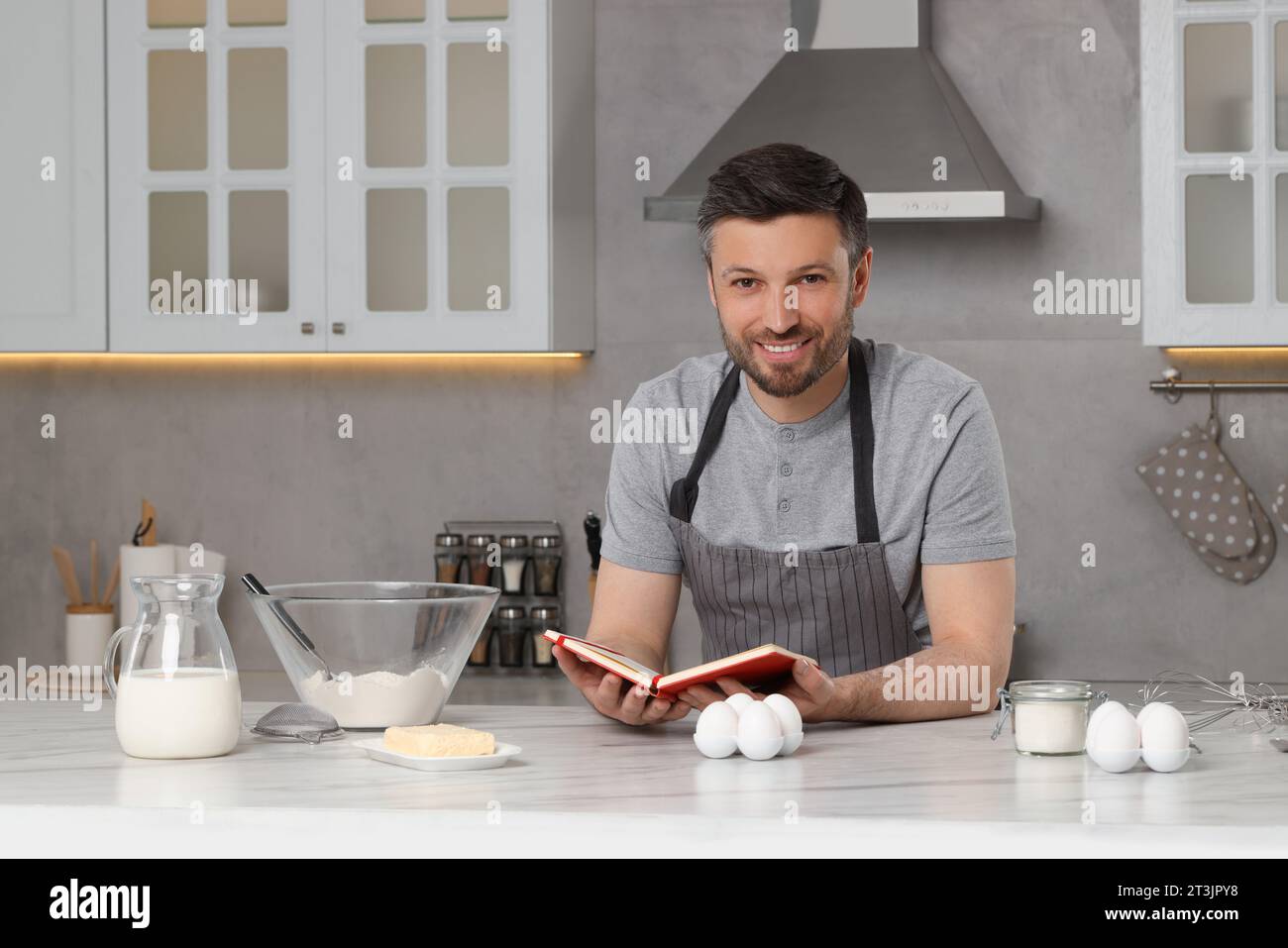 Happy man cooking by recipe book in kitchen Stock Photo