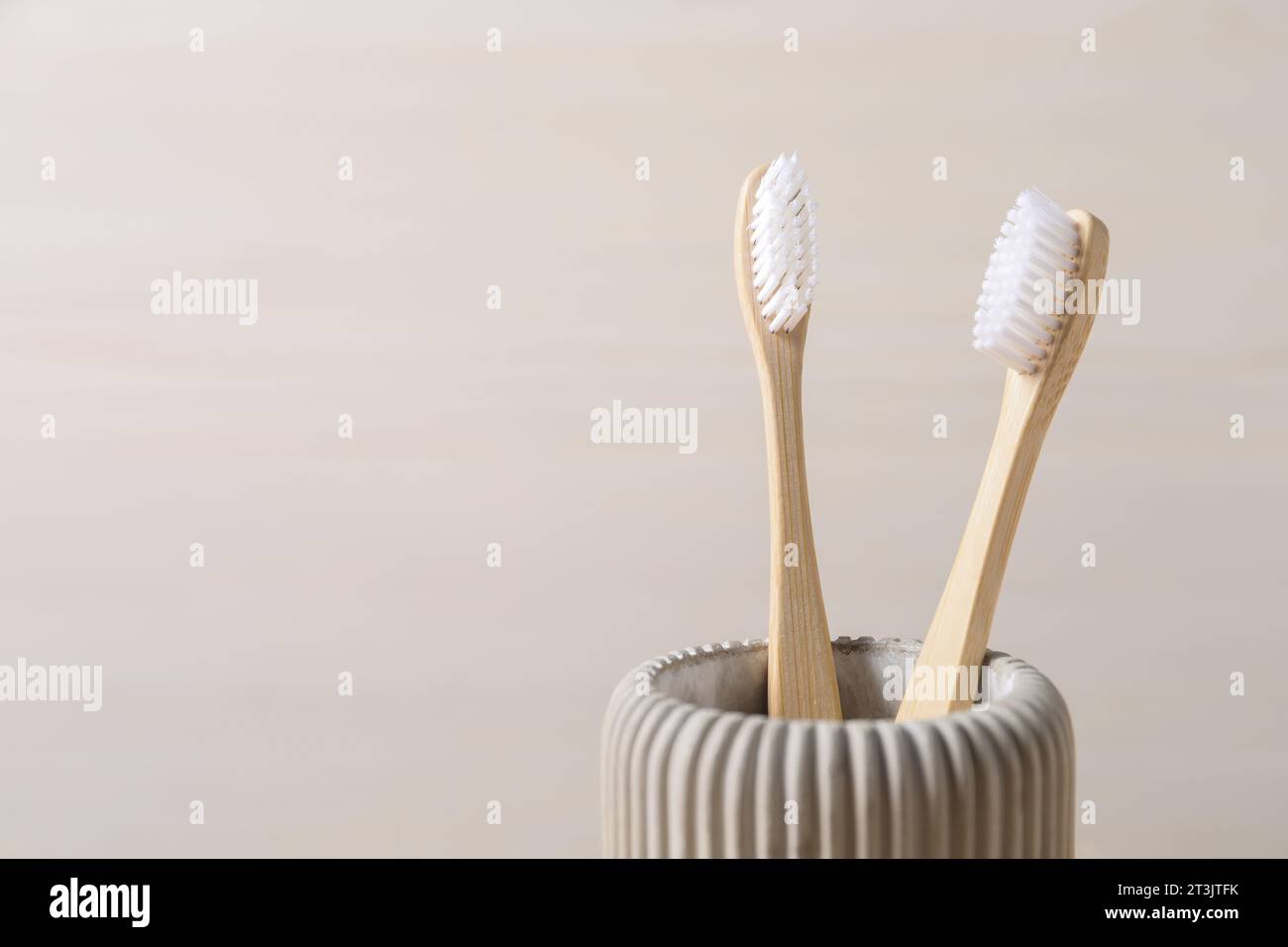 Bamboo toothbrushes in holder on light background, closeup. Space for ...